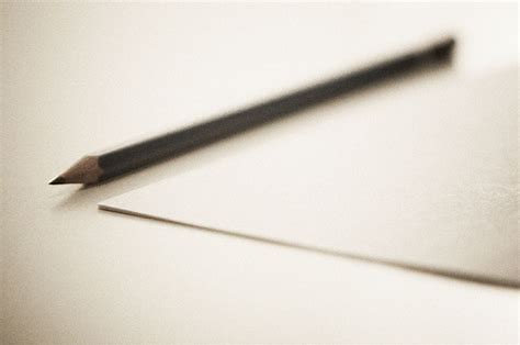 Sharp pencil resting by a blank sheet of paper